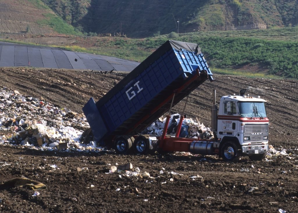 A dump truck performing a property cleanout on a hill.