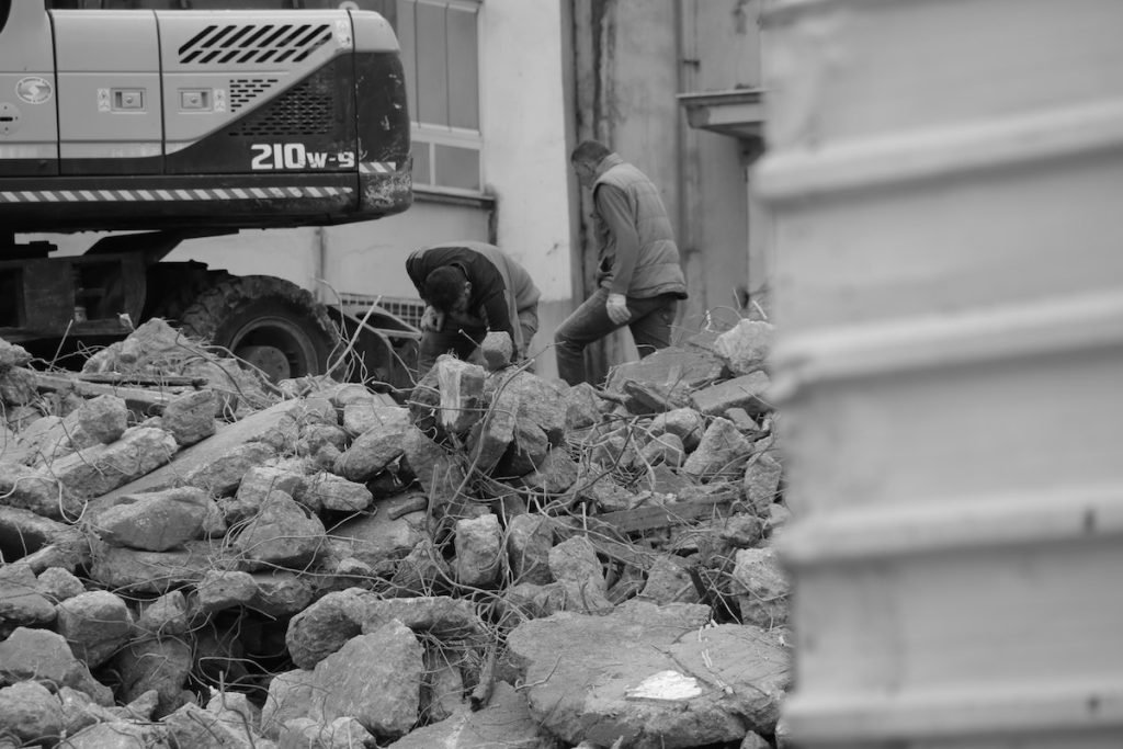 A black and white photo of men working on a pile of rubble during a property cleanout.
