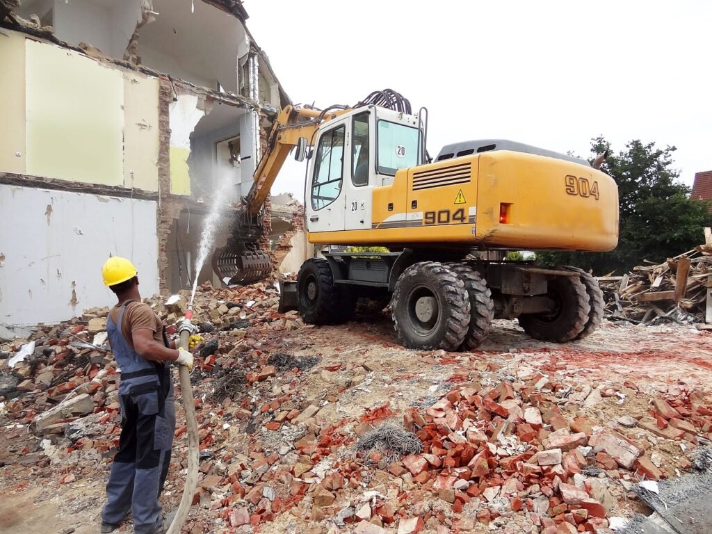 A demolition contractor is working in front of a building that has been demolished.