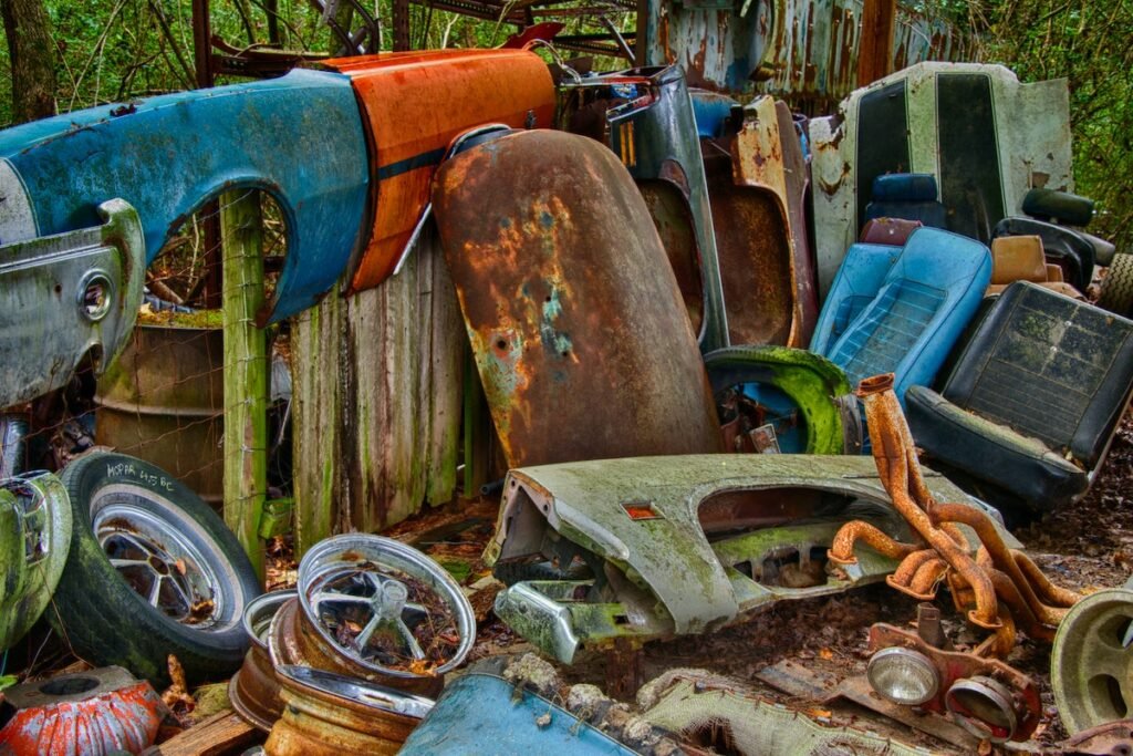 A pile of rusty cars in a wooded area requiring junk removal services.
