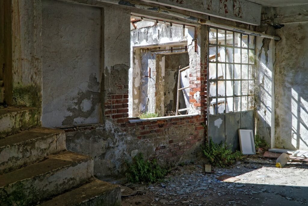 An abandoned building with stairs and a window in need of a property cleanout.