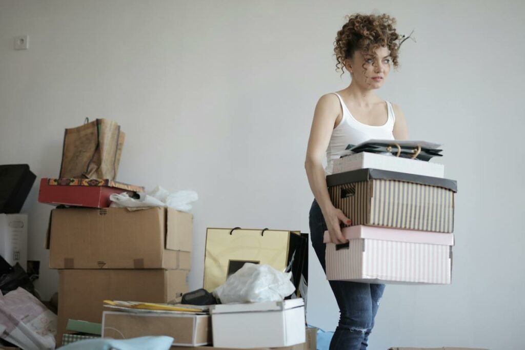 A woman carrying a stack of boxes in her home, utilizing Hauling Services.