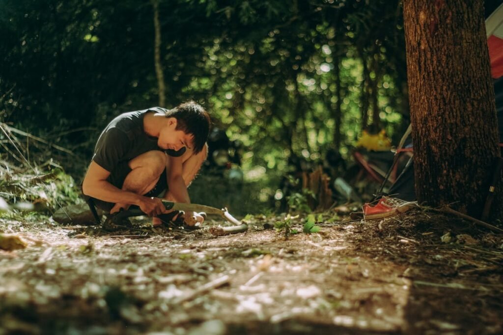 A man crouching down in the woods near a tent, overseeing property cleanout activities.